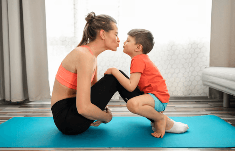 A mother and son sharing a loving kiss during a 'Total Body Burner' workout for moms at home, demonstrating a fun fitness moment on an exercise mat.